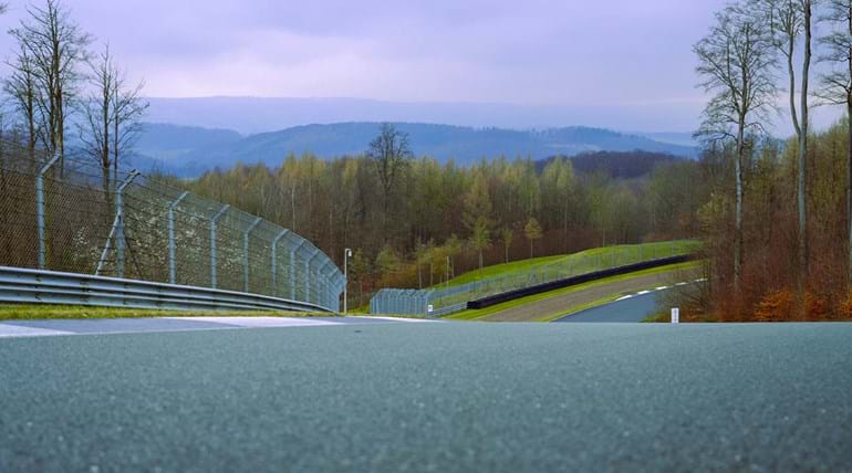 Close up foreground shot of a section of a race track, with a forested landscape in