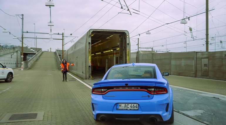 A blue sports car about to board a Eurotunnel Le Shuttle train