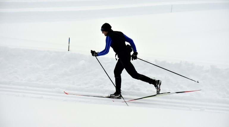 Cross-country skier skiing across snow 