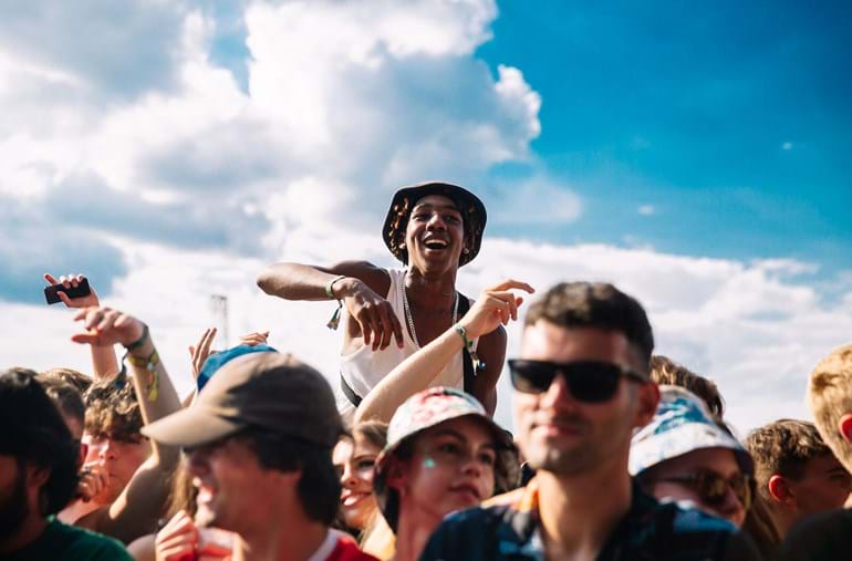 Jongen zit op schouders in menigte festivalgangers