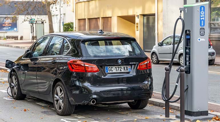 A BMW electric car charging up at a charging station on a city street in France 