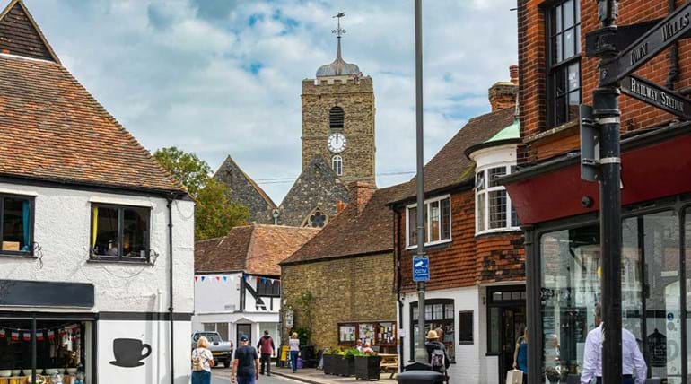 Kruispunt in een historisch stadje, met wandelaars en op de achtergrond een kerktoren