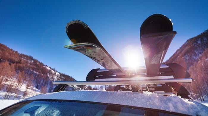 Skis strapped up to a roof rack, ready to hit the slopes.